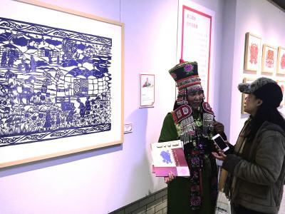 参加中央美院研修研习培训的学员在结业展上向观众讲述自己的剪纸作品.jpg