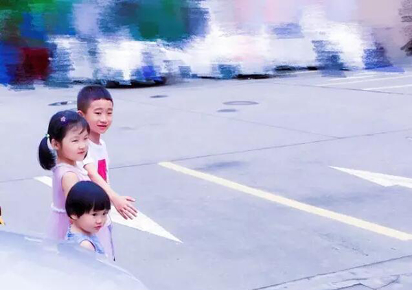 01：过马路的小哥哥下意识把手臂抬起，生怕妹妹们受到伤害。他说：“要听妈妈的话，守规矩；不能让爸妈为我们的安全担心。”.jpg