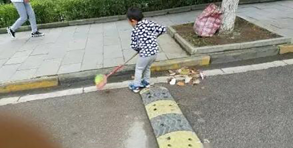 06：路边，还带着围嘴的小孩儿帮爸爸扫起了落叶。他说：“大冷天儿！我想让爸爸早点儿扫完地，爸爸说他腰疼呢。”.jpg