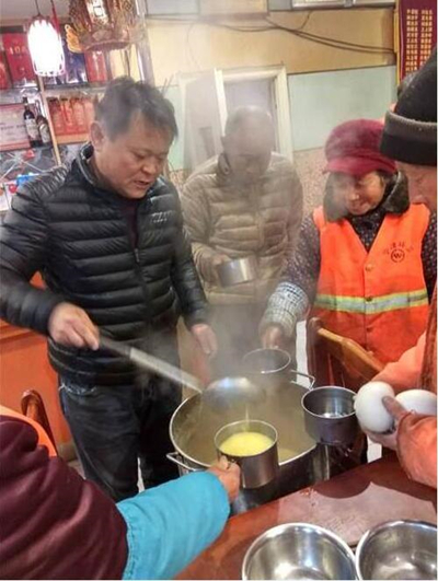 谢金虎（左）给环卫工人盛玉米粥。.jpg
